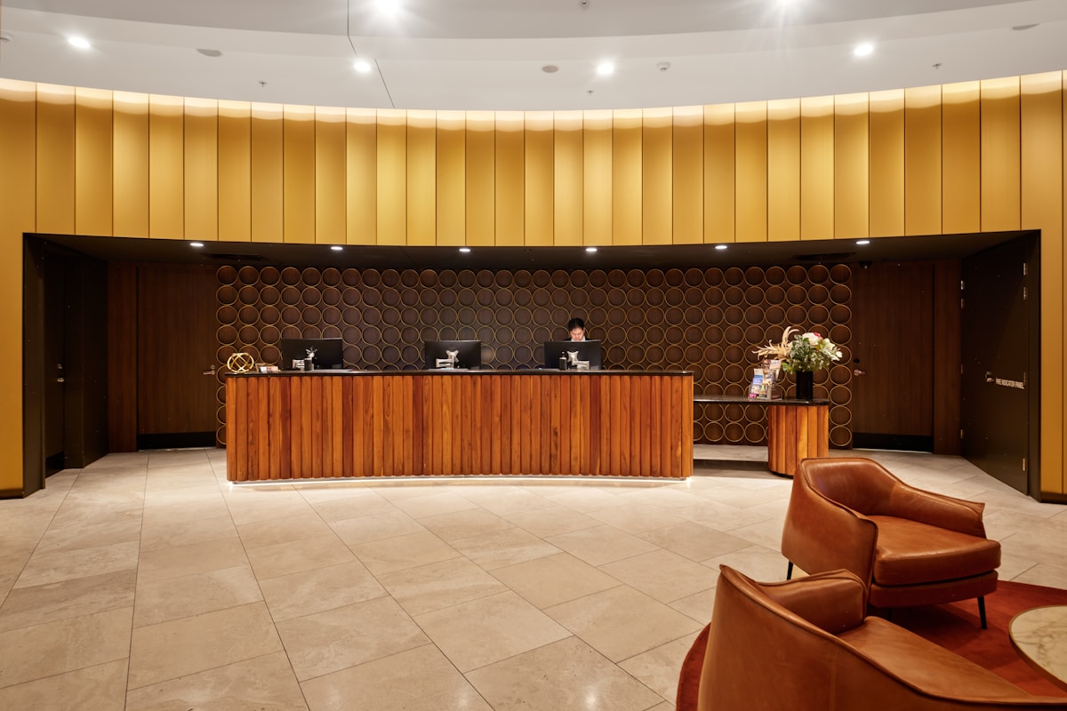A warmly lit hotel reception desk with an agent working at a terminal — the system of record where autonomous software now executes work end to end