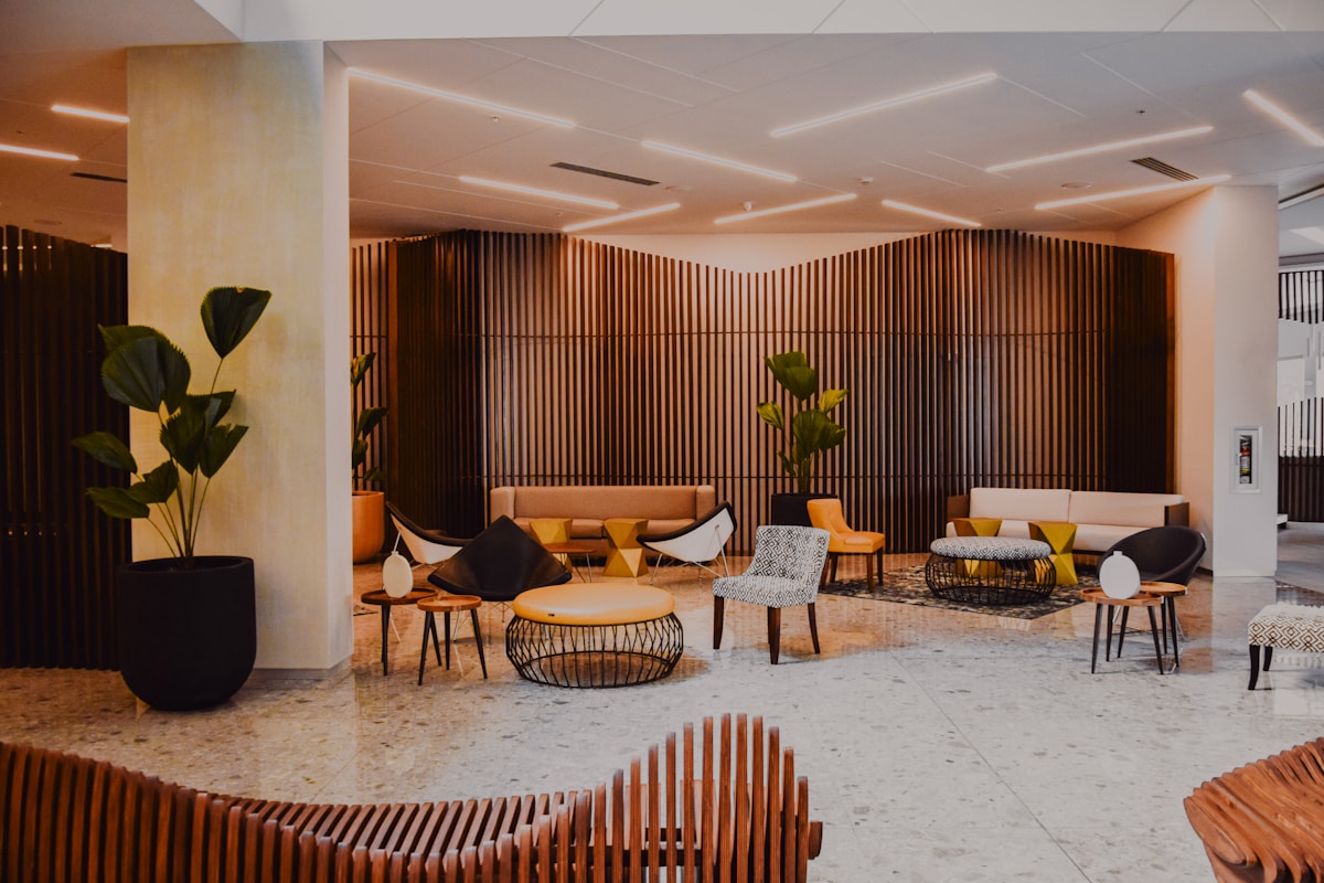 A warmly lit modern hotel lobby with designer furniture and wood-slat walls