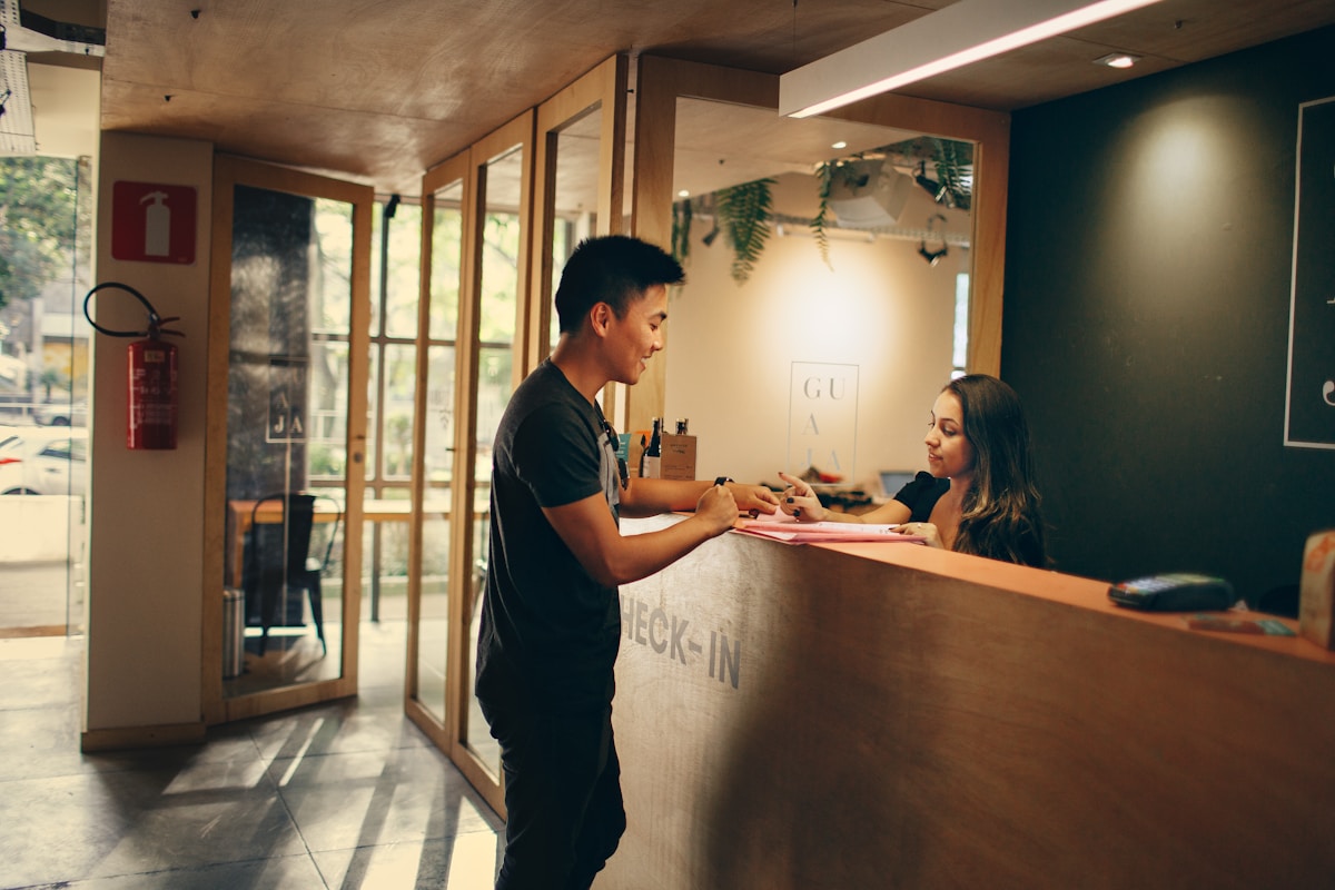 A guest checking in with a front desk agent at a warmly lit hotel reception counter
