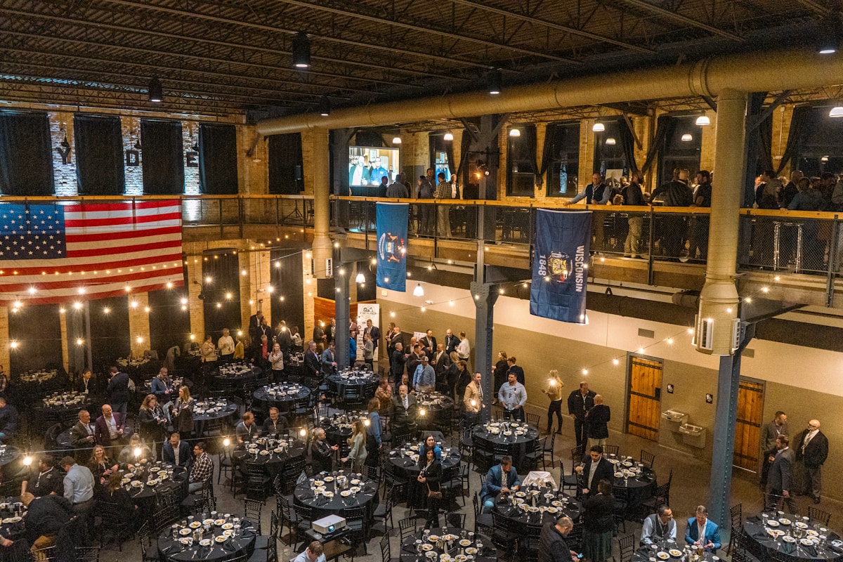 Warm, brick-and-timber hotel banquet hall filled with attendees at round tables during a convention reception — the group demand that drives a convention hotel's rate calendar