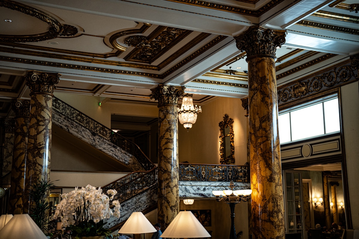 Grand historic hotel lobby with marble columns, ornate gilded plasterwork, a sweeping staircase and crystal chandeliers — the kind of protected interior that rules out conventional wiring