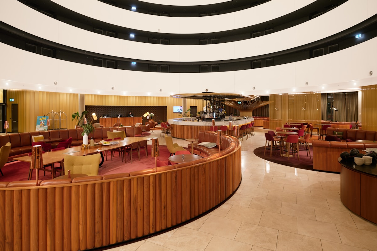A hotel atrium lobby with a curved wooden bar, banquette seating, and tiers of guest-room balconies above, the kind of layout a digital twin is built to simulate