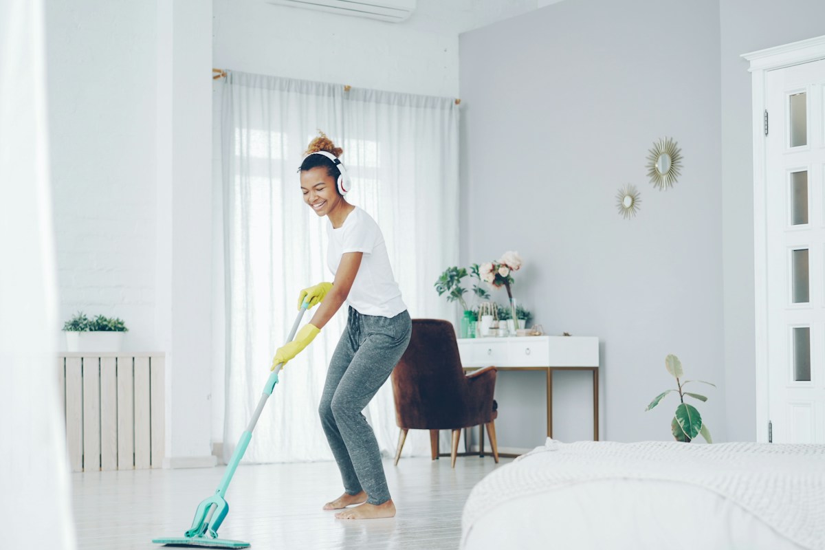A housekeeper cleaning a bright hotel room, the frontline service labor a delivery robots ROI is measured against