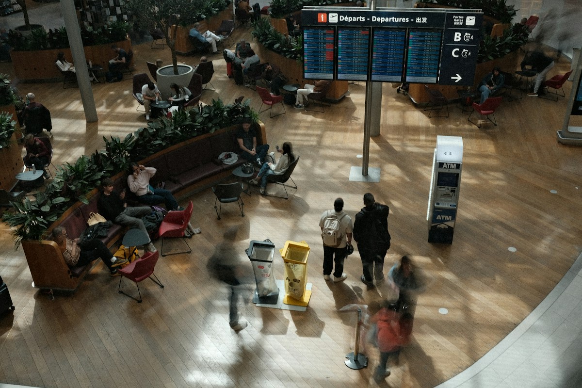 Travelers in an airport terminal beneath a departure board, the wholesale and distribution channels that fill rooms
