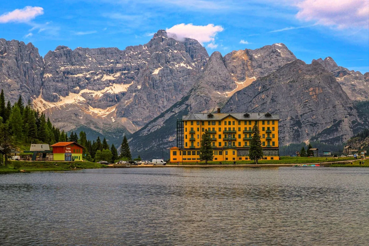 Grand alpine hotel on a mountain lake with Dolomite peaks